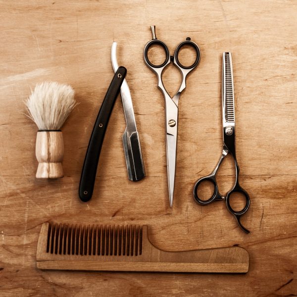 two-scissors-a-dangerous-razor-a-brush-and-a-wooden-comb-lie-in-the-middle-on-a-wooden-table-barber-tool-on-a-wooden-background